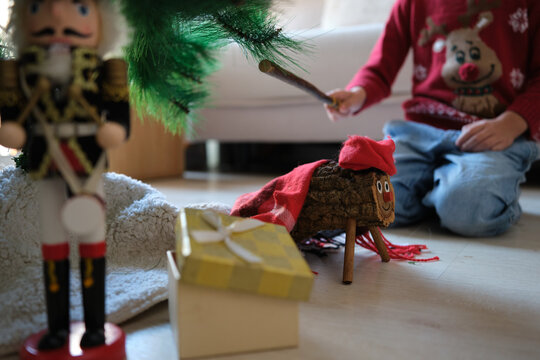 Children hitting caga ti&oacute; log with a stick for gifts under christmas tree