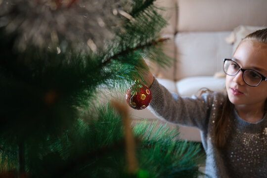 Little girl decorating christmas tree at home
