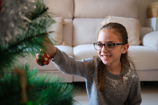 Little girl decorating christmas tree at home