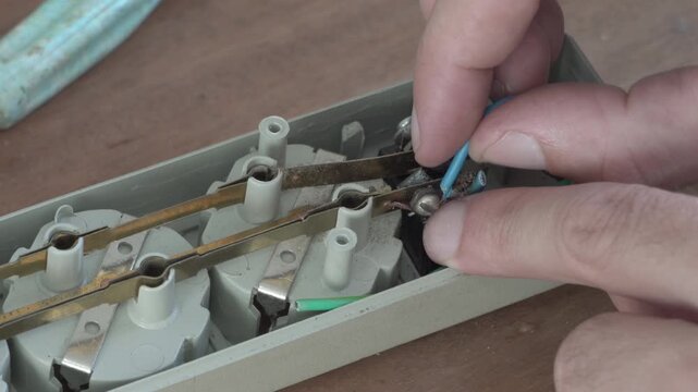 Close-up of repairing an electrical extension cord and connecting wires, Man fixing internal wires and contacts of a power outlet strip