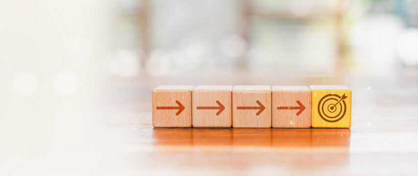 Wooden blocks form a step by step path toward a target, symbolizing business strategy, planning, progress, goal setting, focus, achievement, success, growth, direction, and strategic execution.