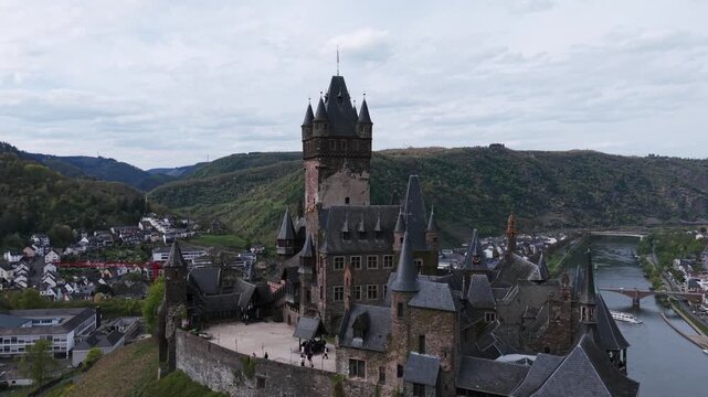 Cochem Castle on a hill overlooking the town and the Moselle river in Germany. Aerial forward