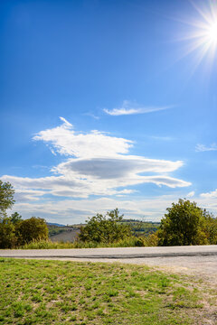 Rural road beneath lenticular clouds and rolling hills in the Montefeltro region of Marche, Italy