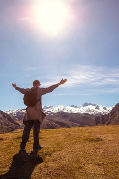 A man with hands in the air on the top of mount looks at beautiful panorama of the mountains. National Park Peaks of Europe. Cantabria, Spain, Europe