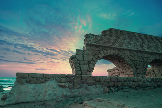 Aqueduct in ancient city Caesarea at sunset. Trendy purple color