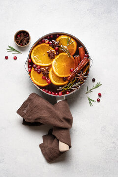 Hot mulled wine with cranberries, orange, rosemary, cinnamon and spices in a pot, Christmas winter drink on a light background with copy space