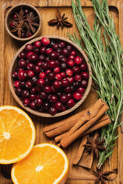 Ingredients for a cranberry orange winter drink with rosemary, cinnamon and spices on a wooden cutting board, autumn seasonal food