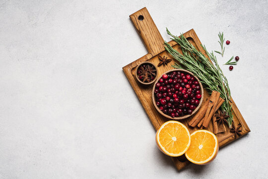 Ingredients for a cranberry orange winter drink with rosemary, cinnamon and spices on a wooden cutting board, autumn seasonal food