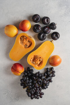 Autumn still life with butternut pumpkins, nectarines, plums and grapes on a light background, seasonal fresh fruits and vegetables harvest concept