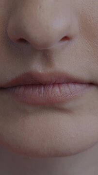 Close-up of anonymous woman pursed lips expressing discontent on black color background. Human emotion and face expression concept.