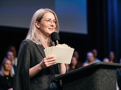 Generative AI, Woman presenting on stage with a microphone at a conference or awards event