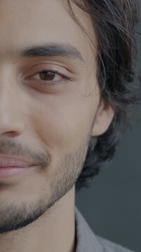Close-up portrait of joyful Middle Eastern man half face looking at camera and smiling on black background. Positive emotion and people concept.
