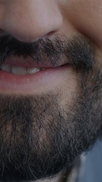 Close-up of female mouth smiling while bearded man looking at camera on black background. Positive emotion and human body part concept.