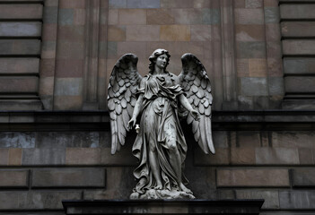 Fototapeta premium Spirituality and religion concept stone angel statue with wings on a historic building mourning and peace architectural detail in the city