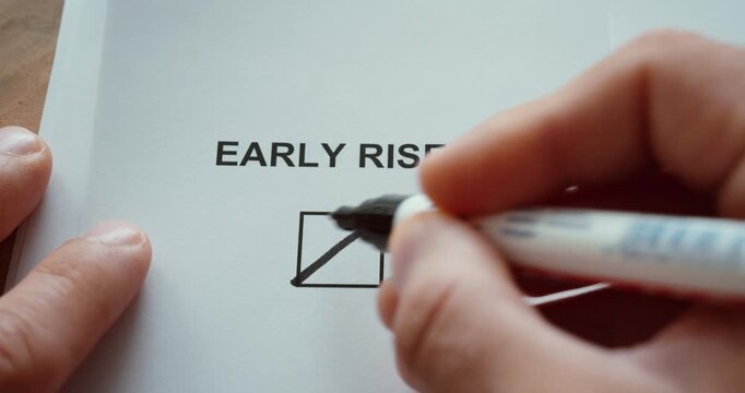 Close-up of a hand marking the early riser checkbox on a paper form, representing morning habits and daily routine.