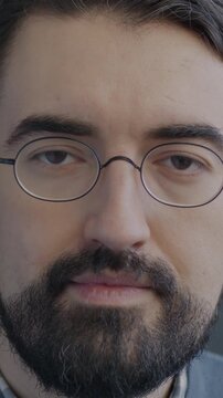 Slow motion portrait of confident Middle Eastern man in glasses looking at camera on black studio background. People and face expression concept.