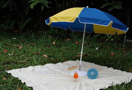 Summer vacation and holiday leisure, beach umbrella with tropical cocktail on a picnic blanket in a garden for outdoor relaxation and travel lifestyle