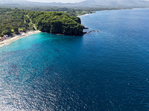 Aerial view of Bukit Asah coast with lush green cliffs and blue ocean in Bali, Indonesia