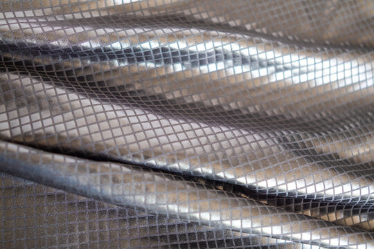 Folded metallic silver fabric with square grid texture and reflective shimmer for design