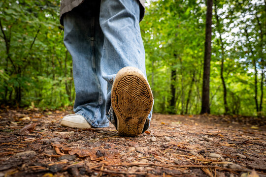Close-Up of Muddy Sneaker Sole on a Green Forest Trail