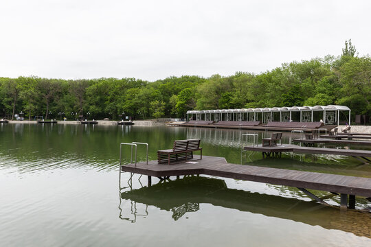 Coastal view of Resort lake located in the resort area of Zheleznovodsk at the bottom of the Cascade Staircase. Empty wooden docks and benches extend over a calm lake