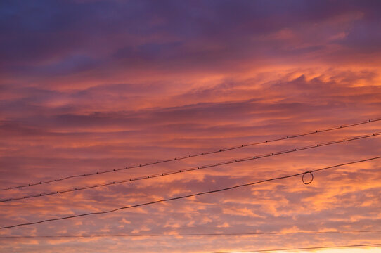 Dramatic sunset sky background with purple and orange clouds and diagonal power lines
