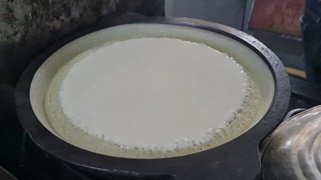 Pancake Batter Cooking in a Hot Pan with Bubbles Forming Around the Edge