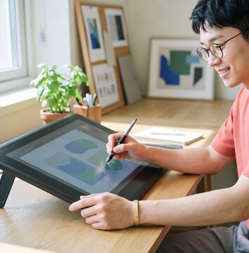 Generative AI, Asian male graphic designer drawing on a pen display tablet in a home studio 