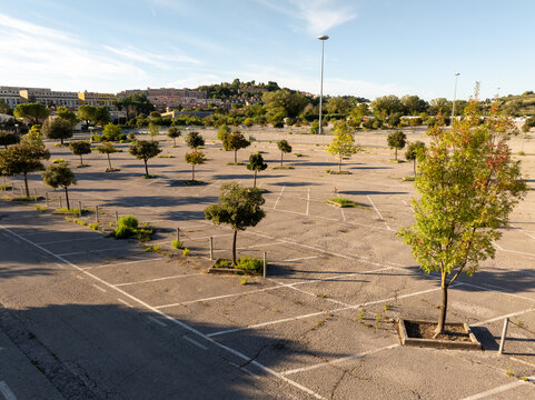 Aerial view of an empty parking lot with scattered trees and marked parking spaces in Ancona, Marche, Italy.