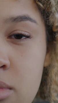 Close-up of African American lady half face looking at camera on black color background. Human emotion and body part concept.