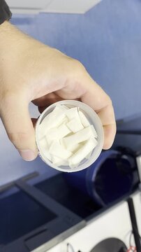 Close-up of a hand holding a container filled with white nicotine pouches, representing smokeless nicotine and oral tobacco alternatives.