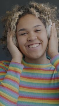 Portrait of African American woman wearing headphones dancing on black background. Audio device and entertainment concept.