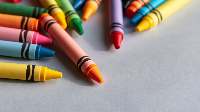 Multicolored crayons scattered on a light gray background, top view with space for text, school and preschool fine arts materials, with copy space