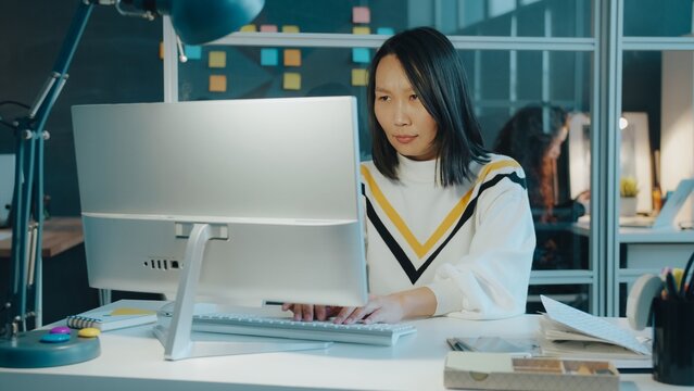 Angry Asian businesswoman is working with computer typing then leaving workplace unhappy with outcome. Business, people and emotions concept.