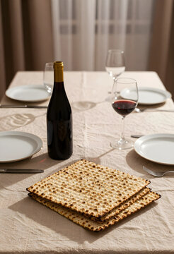 Passover seder table with matzah and wine, traditional Jewish holiday celebration with unleavened bread and red wine glasses on a linen tablecloth