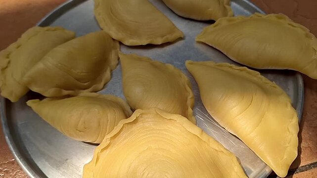 Uncooked Indonesian savory pastry on a plate, ready for frying; homemade raw empanada preparation.