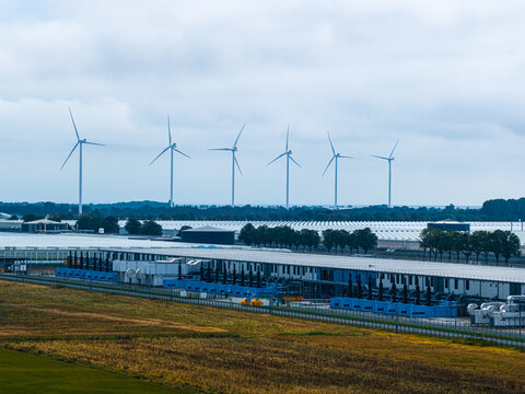 Aerial view of Agriport A7 wind farm with large industrial greenhouses and wind turbines in the flat landscape of Middenmeer, Noord-Holland, Netherlands.