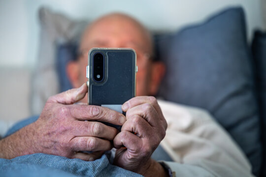 Stockholm, Sweden A man lays in bed with a cell phone.