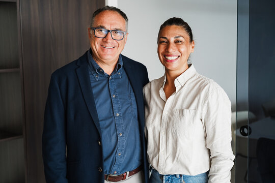 Latin american real estate agents smiling on camera inside business agency office - Entrepreneur and investing concept - Focus on faces - UGC content