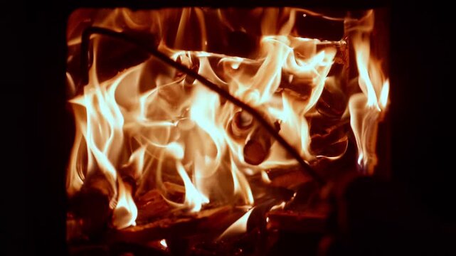 Close-up of bright dancing flames in a fireplace, burning logs and glowing embers