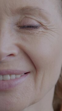 Close-up portrait of cheerful mature woman smiling looking at camera on gray color background. Positive emotion and elderly person concept.
