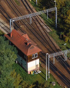 Aerial view of a railway signal box with a red tiled roof located next to multiple railway tracks and overhead power lines in Sosnowiec, Wojewodztwo slaskie, Poland.