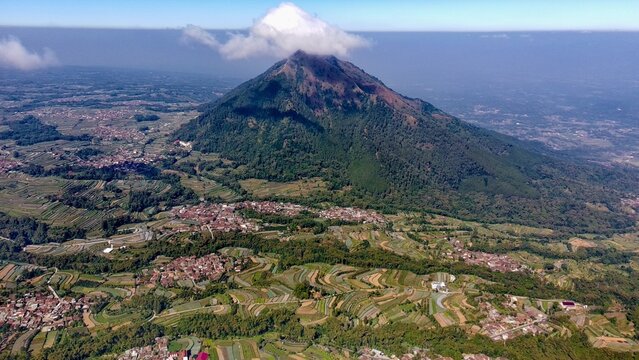 Aerial view of Mount Andong rising above terraced agricultural fields and rural villages in the lush landscape of Ngablak, Central Java, Indonesia.