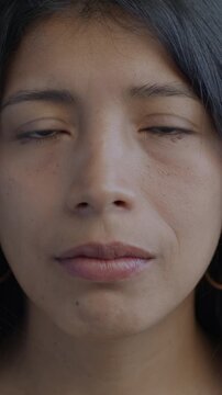 Slow motion portrait of sad Hispanic woman looking at camera crying on black background. Negative emotion and unhappy people concept.