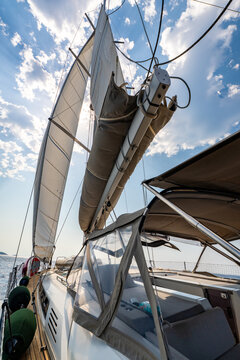 Low angle view of sailing yacht with fully deployed sails, taut rigging and windblown lines while cruising across Adriatic Sea. Dynamic maritime scene highlighting wind power, seamanship and freedom.