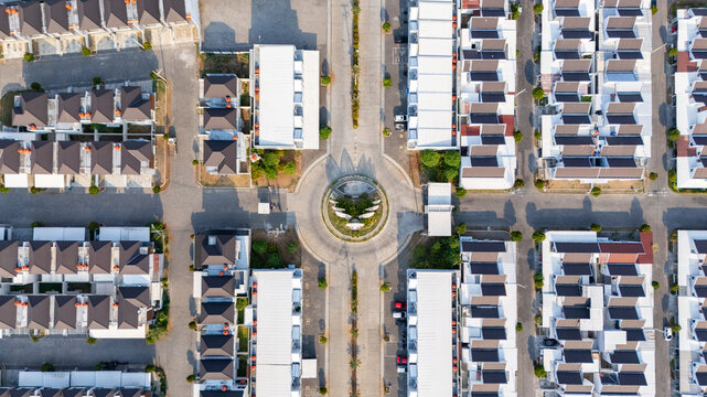 Aerial view of a modern residential complex featuring uniform houses with dark roofs arranged around a central roundabout in a planned neighborhood in Semarang, Central Java, Indonesia.
