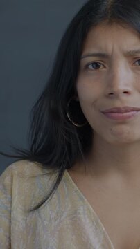 Slow motion portrait of Hispanic lady showing thumbs-down hand gesture and shaking head on black background. Negative emotion and people concept.