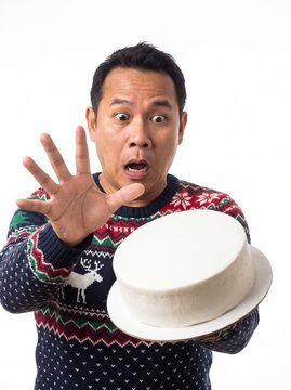 Surprised man dropping Christmas cake in festive sweater