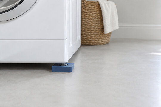 Blue vibration pad installed under one washing machine foot