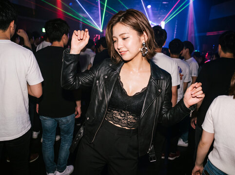 クラブのレーザー照明の中で音楽に合わせて踊る笑顔の若い女性